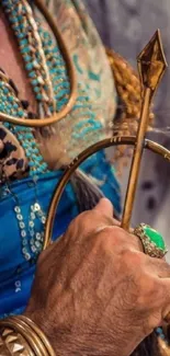 Close-up of a regal hand holding a golden scepter with a green gemstone ring.