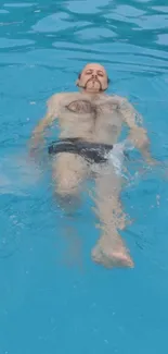 Man floating in a calm blue pool, displaying relaxation.