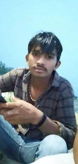 Young man outdoors with smartphone and serene sky.