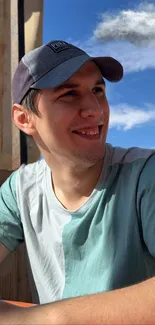 Man in a cap, smiling under clear blue sky.