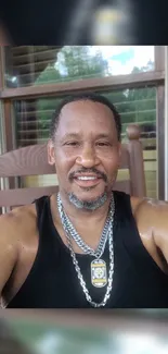 A man smiling on a porch with a wooden backdrop.