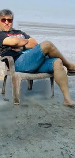 Man relaxing in a chair on a sandy beach.