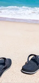 Flip-flops on sandy beach with ocean waves in the background.