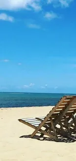 Wooden chairs on a peaceful beach under a blue sky.