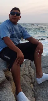 Person relaxing on rocks by the oceanfront under a calm sky.