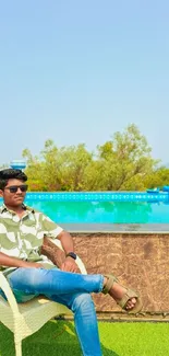 Man relaxing by a vibrant blue pool on a sunny day.