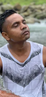 Man relaxing by the riverbank in nature, with a calm and peaceful expression.