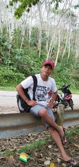 Traveler relaxing by a forest roadside, surrounded by lush greenery.