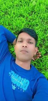 Person in blue shirt relaxing on vibrant green grass.