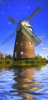 Picture of a windmill reflecting in calm water with a blue sky backdrop.