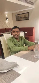 Young man in green shirt at restaurant table.