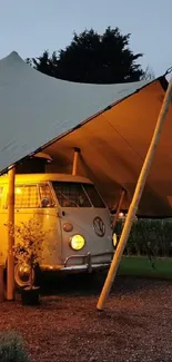 Retro camper van under tent with warm evening light.