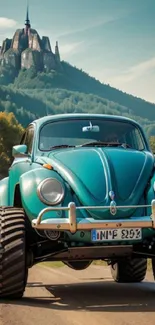 Teal vintage car with large tires in a mountain landscape.