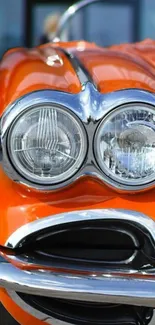 Vintage orange car with chrome headlights and stylish design.