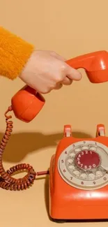 Retro orange phone on beige background.