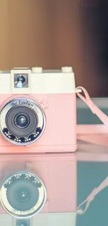 Retro pink camera with reflection on glass surface.