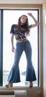 Person posing stylishly on window ledge in natural light.