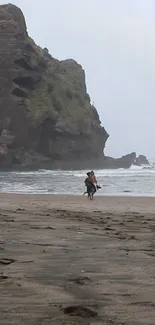 Horse rider on a misty beach with rocky cliff in view.