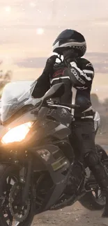 Rider on a black motorcycle at sunset in a desert landscape.