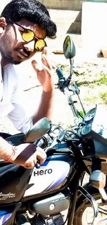 Man in sunglasses on a Hero bike, posing confidently outdoors.