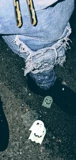 Ripped jeans with ghost stickers on a dark street background.