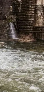 Serene river flowing beside a rustic brick wall.