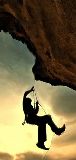 Silhouette of a rock climber against a sunset sky on a rugged cliff.