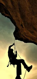 Silhouette of a rock climber at sunset with golden skies.