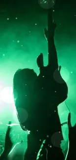 Silhouette of a guitarist at a rock concert with vibrant green lighting.