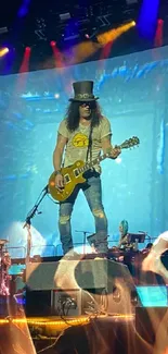 Iconic rock guitarist performing live on stage with vibrant blue lights.