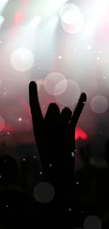 Silhouette of rock hand sign with bright concert lights in the background.