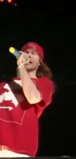 Rockstar singing passionately in vibrant red outfit on stage.