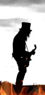 Silhouette of a rockstar playing guitar against a cloudy sky in black and white.