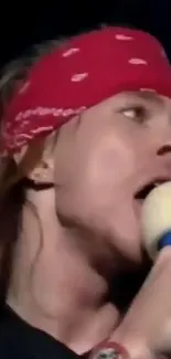 Rockstar singing with red bandana and microphone close-up.