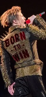 Performer in spiked jacket with 'Born to Win' on stage.