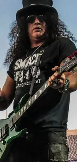 Rock guitarist holding an electric guitar on stage with blue sky backdrop.