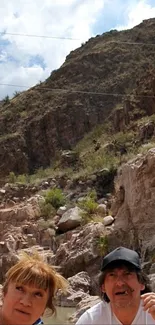 People explore rocky canyon landscape under cloudy sky.