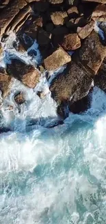 Aerial view of waves crashing against rocks on a cyan blue coastal shoreline.