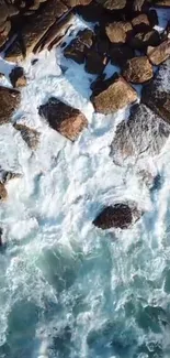 Aerial view of rocky coastline with foaming ocean waves crashing on stones.