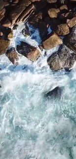 Aerial view of waves crashing on rocky shoreline; mobile wallpaper with ocean scenery.