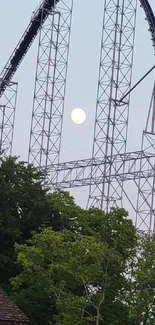 Roller coaster under moonlit sky with trees and scenic view.