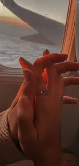 Romantic hands in airplane against sunset view.