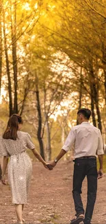 A couple walks hand-in-hand through a golden forest in autumn.