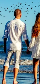 A couple holding hands by the ocean at sunset.