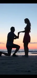 Silhouette of a romantic beach proposal at sunset.