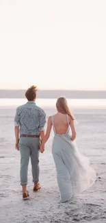 Couple walking on a tranquil beach at sunset, creating a serene and romantic scene.