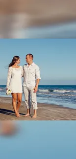 Couple walking on a serene beach with clear blue sky.