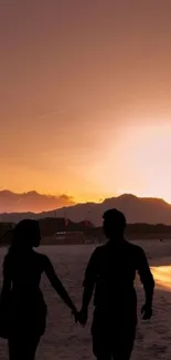 Couple's silhouette on a beach at sunset with a vivid orange sky.