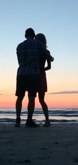 Silhouette couple embracing on a beach at sunset with ocean in background.