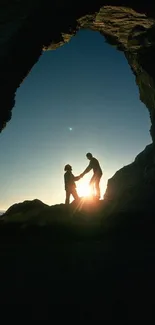 Silhouette of couple at sunset under a natural rock arch by the beach.